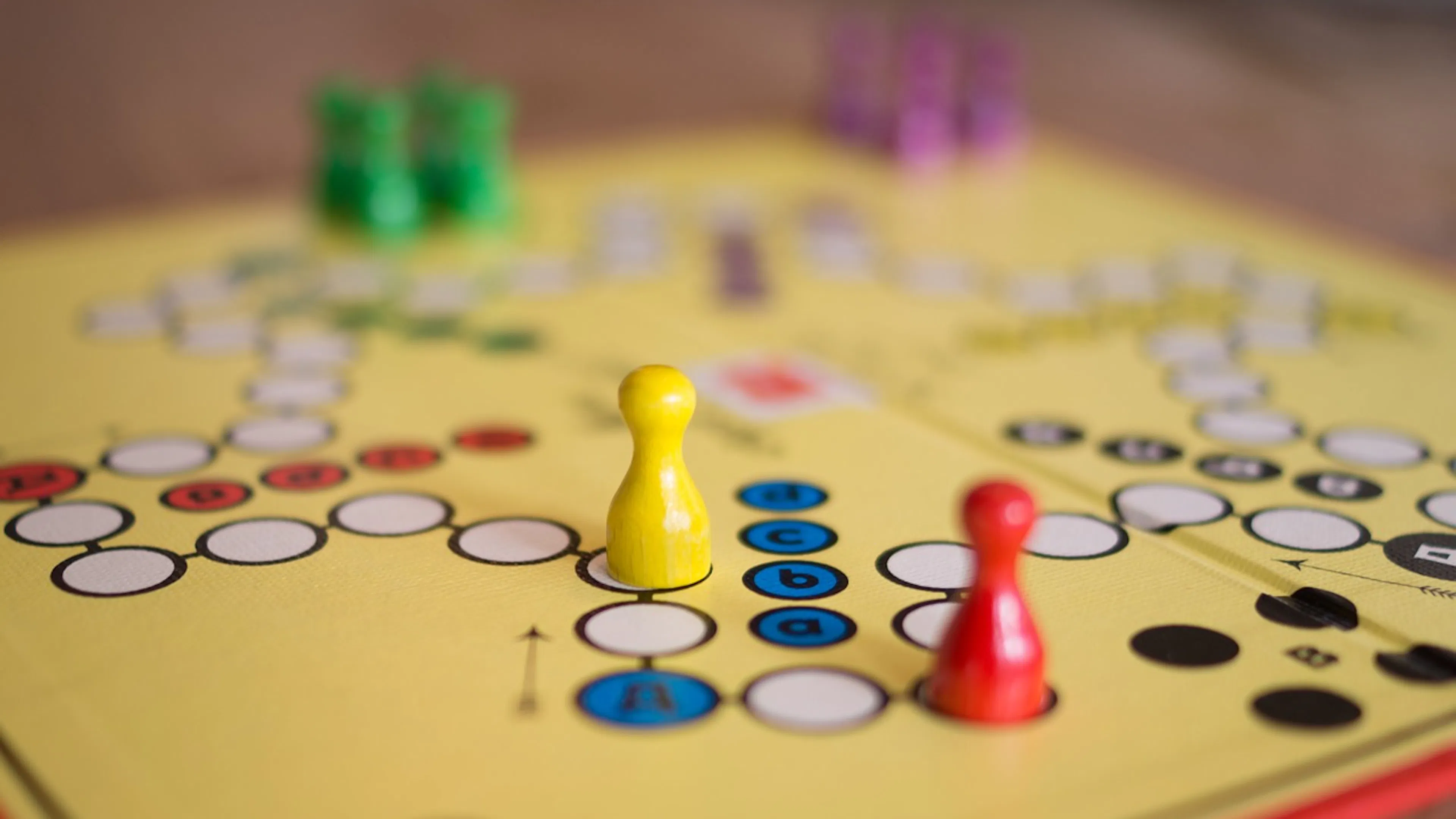 A wooden board game with yellow red and green pieces on top of it