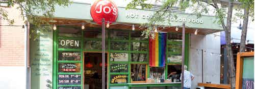 Close up of Jo’s restaurant exterior on the first level of AMLI Downtown with red sign and rainbow flag hanging near entrance