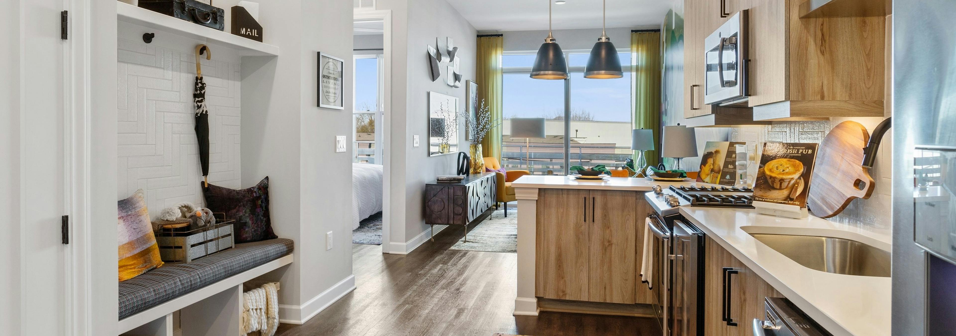 Interior of AMLI Westside apartment kitchen with hardwood floors and built in nook with cushioned bench and coat hangers