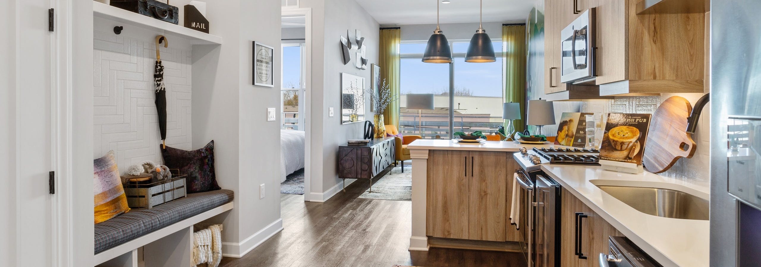 Interior of AMLI Westside apartment kitchen with hardwood floors and built in nook with cushioned bench and coat hangers