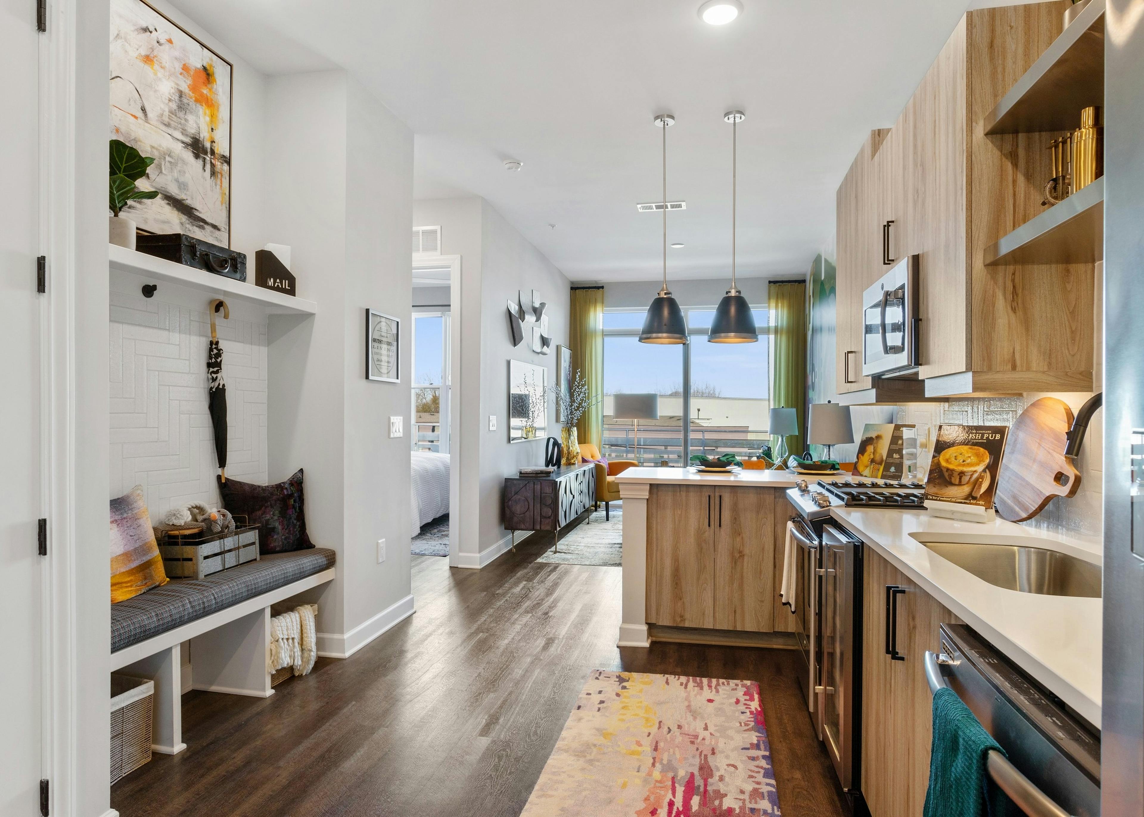 Interior of AMLI Westside apartment kitchen with hardwood floors and built in nook with cushioned bench and coat hangers