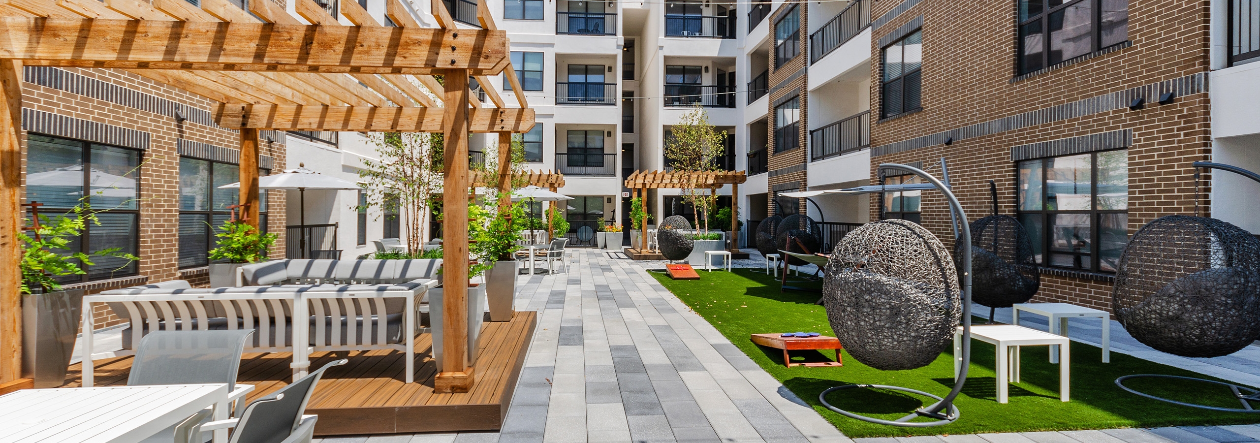 AMLI Quadrangle courtyard with wood pergolas with abundant seating and grassy areas hanging basket swing chairs