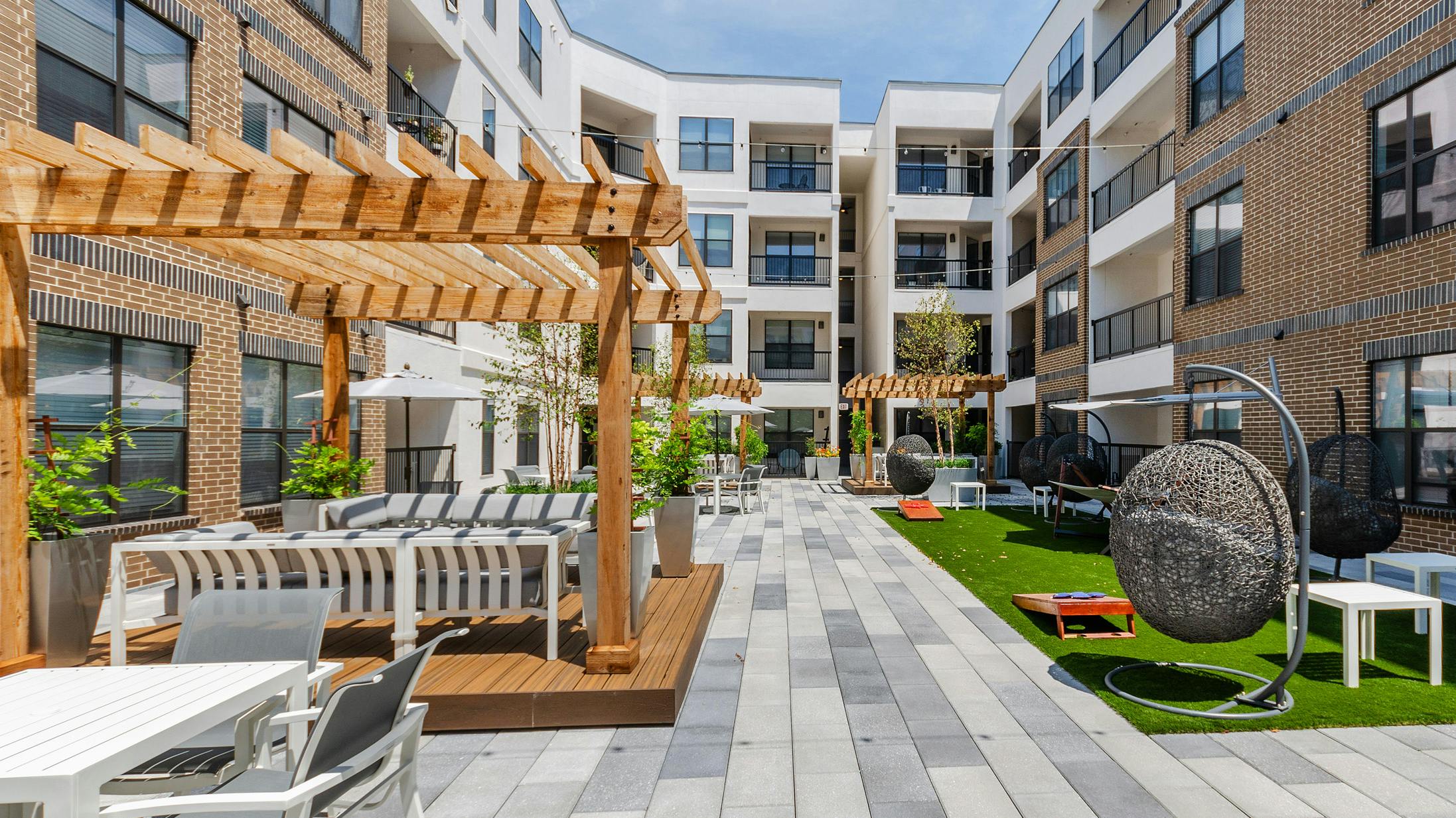 AMLI Quadrangle courtyard with wood pergolas with abundant seating and grassy areas hanging basket swing chairs