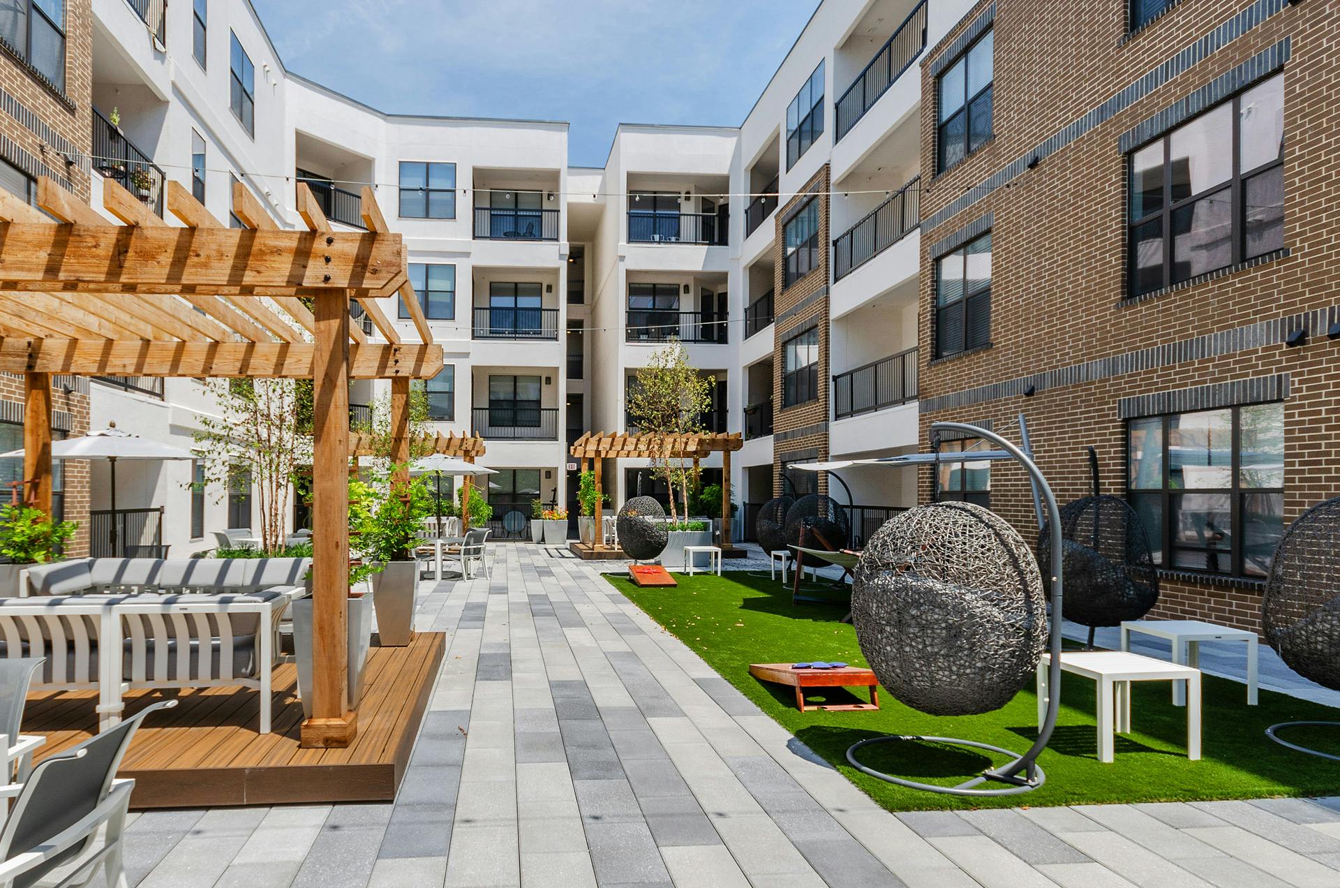 AMLI Quadrangle courtyard with wood pergolas with abundant seating and grassy areas hanging basket swing chairs