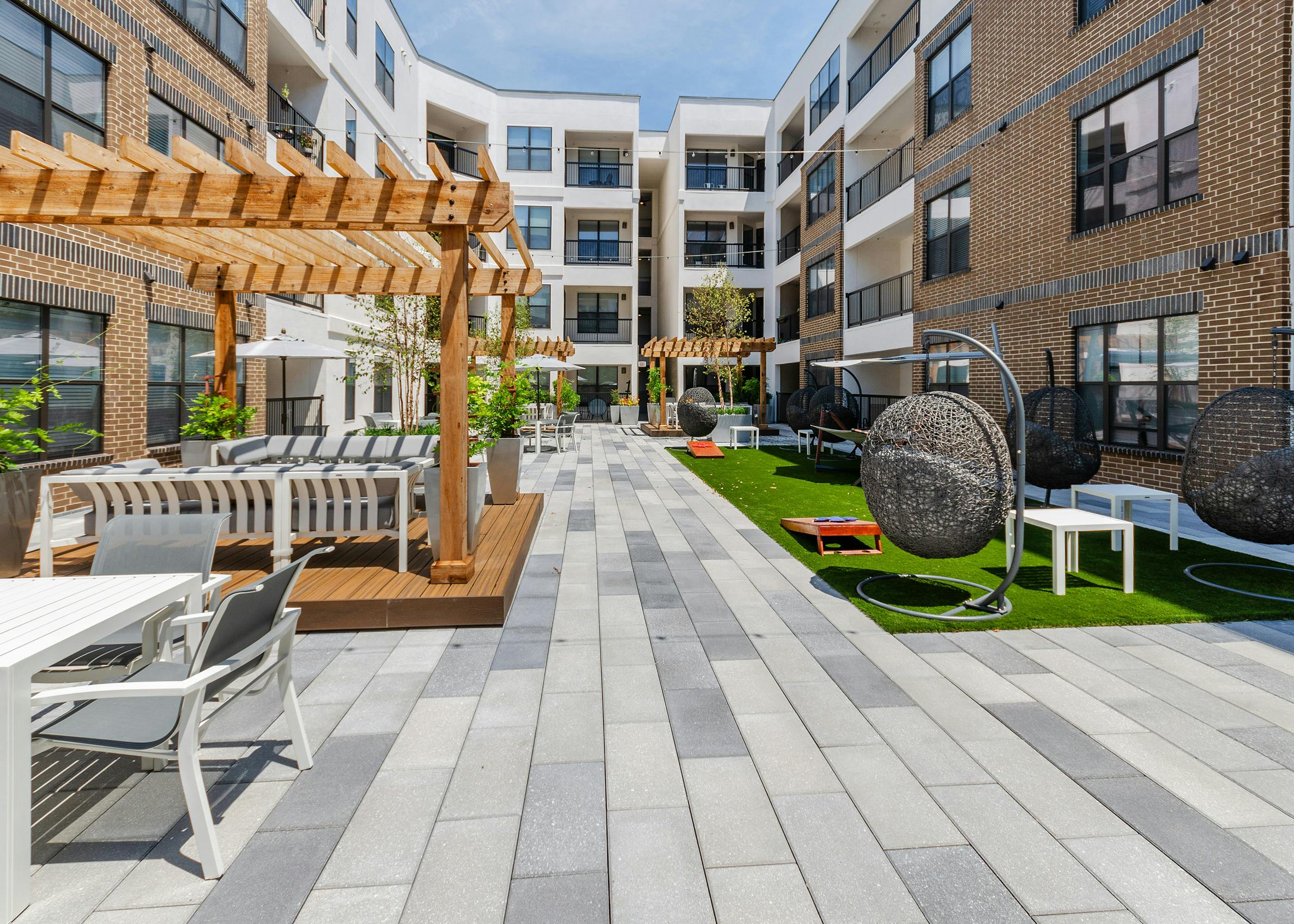 AMLI Quadrangle courtyard with wood pergolas with abundant seating and grassy areas hanging basket swing chairs