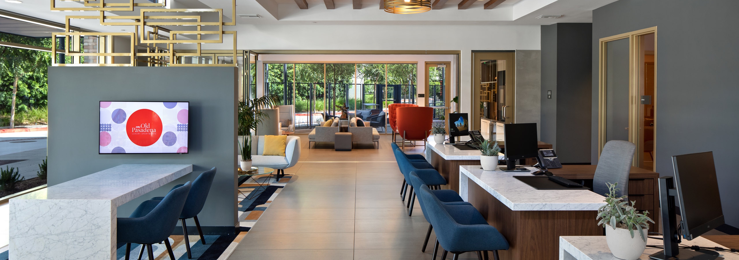 AMLI Old Pasadena leasing office with stylish décor and big screen TV and three white desks with blue guest chairs