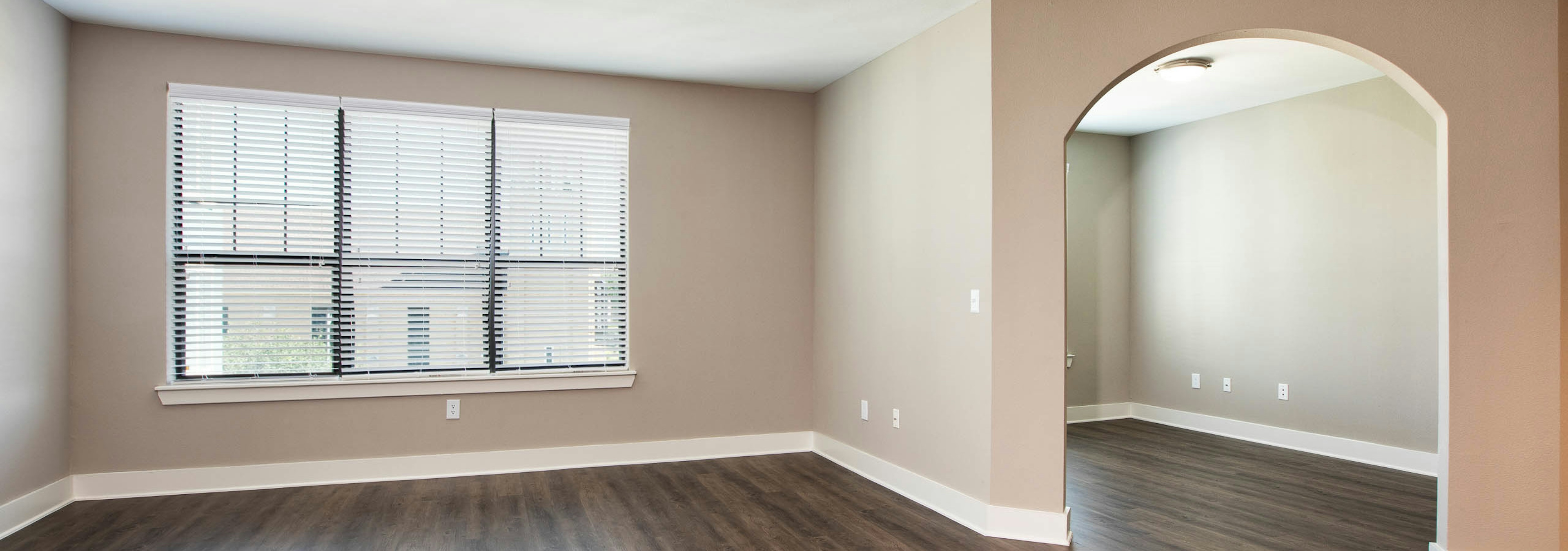 Interior view of living room at AMLI Eastside with dark hardwood and light walls with white trim and a bright window