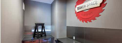 Makers space amenity at AMLI on Aldrich with grey walls and tables for creating and a red wall piece reading Makers Space