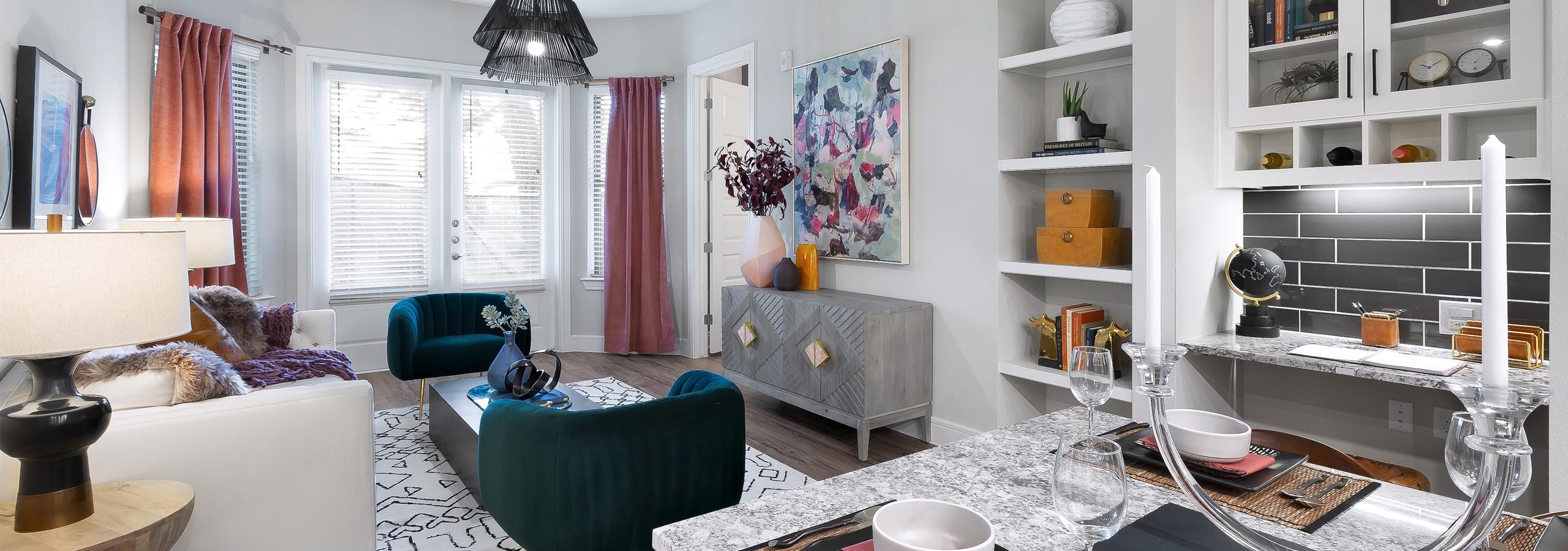 Living room at AMLI Lakeline apartments with plush colorful seating and large bay windows shaded by white blinds