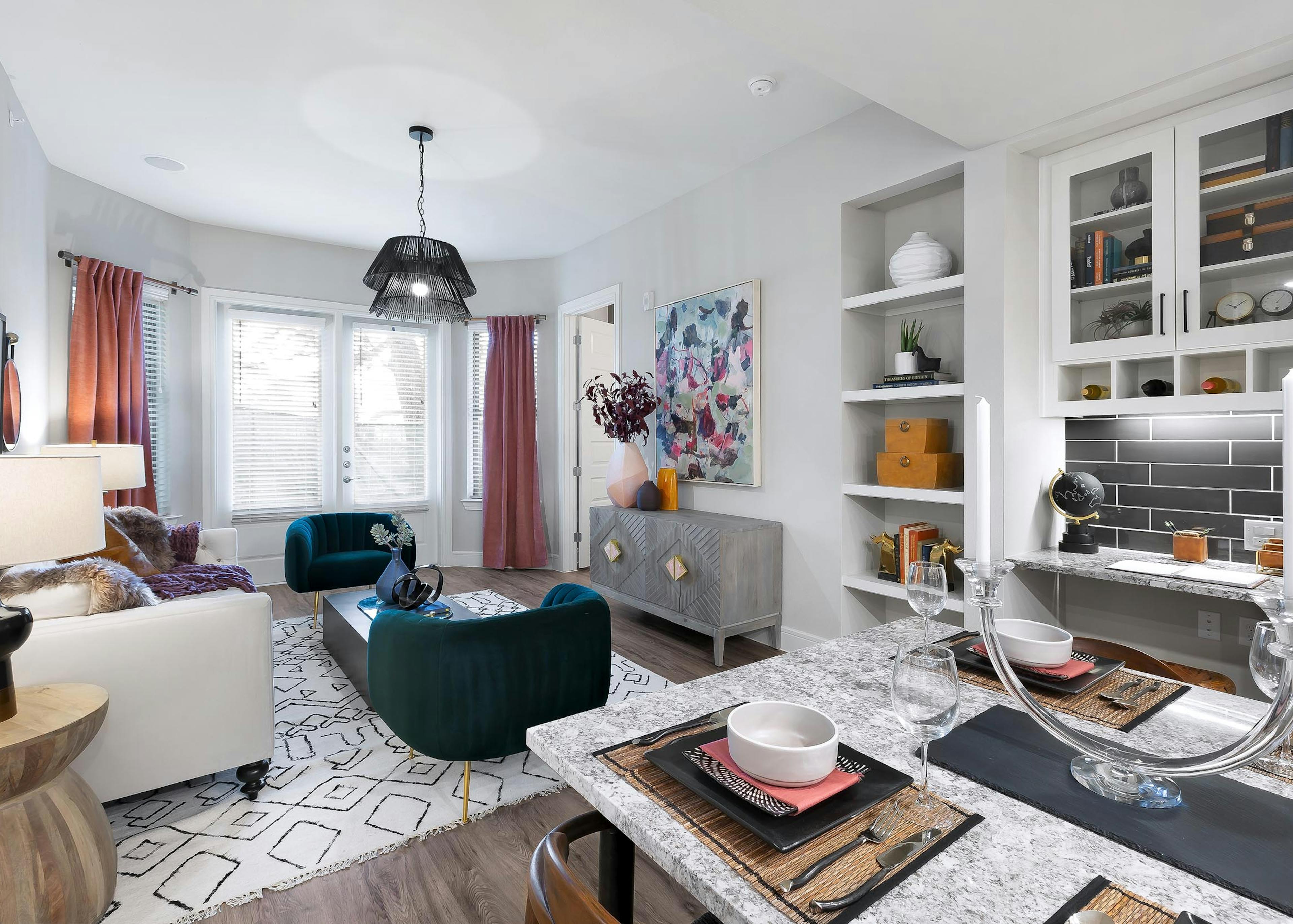 Living room at AMLI Lakeline apartments with plush colorful seating and large bay windows shaded by white blinds