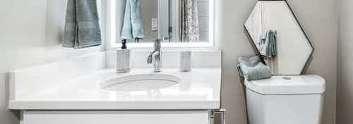 AMLI Bellevue Park apartment bathroom with back it mirror over white quartz vanity with white toilet with mirror on top