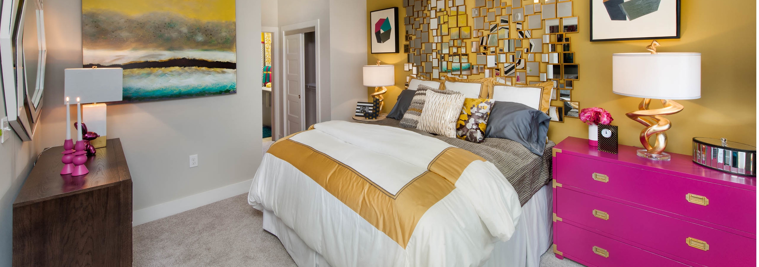 Interior of an AMLI Piedmont Heights bedroom with a gold wall while the others are grey with carpet and bright colorful decor