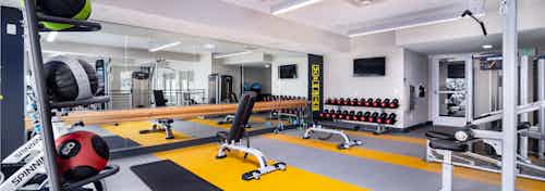 Interior view of fitness center at AMLI Littleton Village apartments with free weights, medicine balls and big screen TV