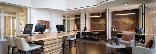 Leasing office at AMLI on Riverside with dark hardwood and grey seating options and a large wooden desk with computers