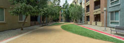 Daytime view of Dog Park with grass, benches and bed of rocks surrounded by trees at AMLI Warner Center apartment building