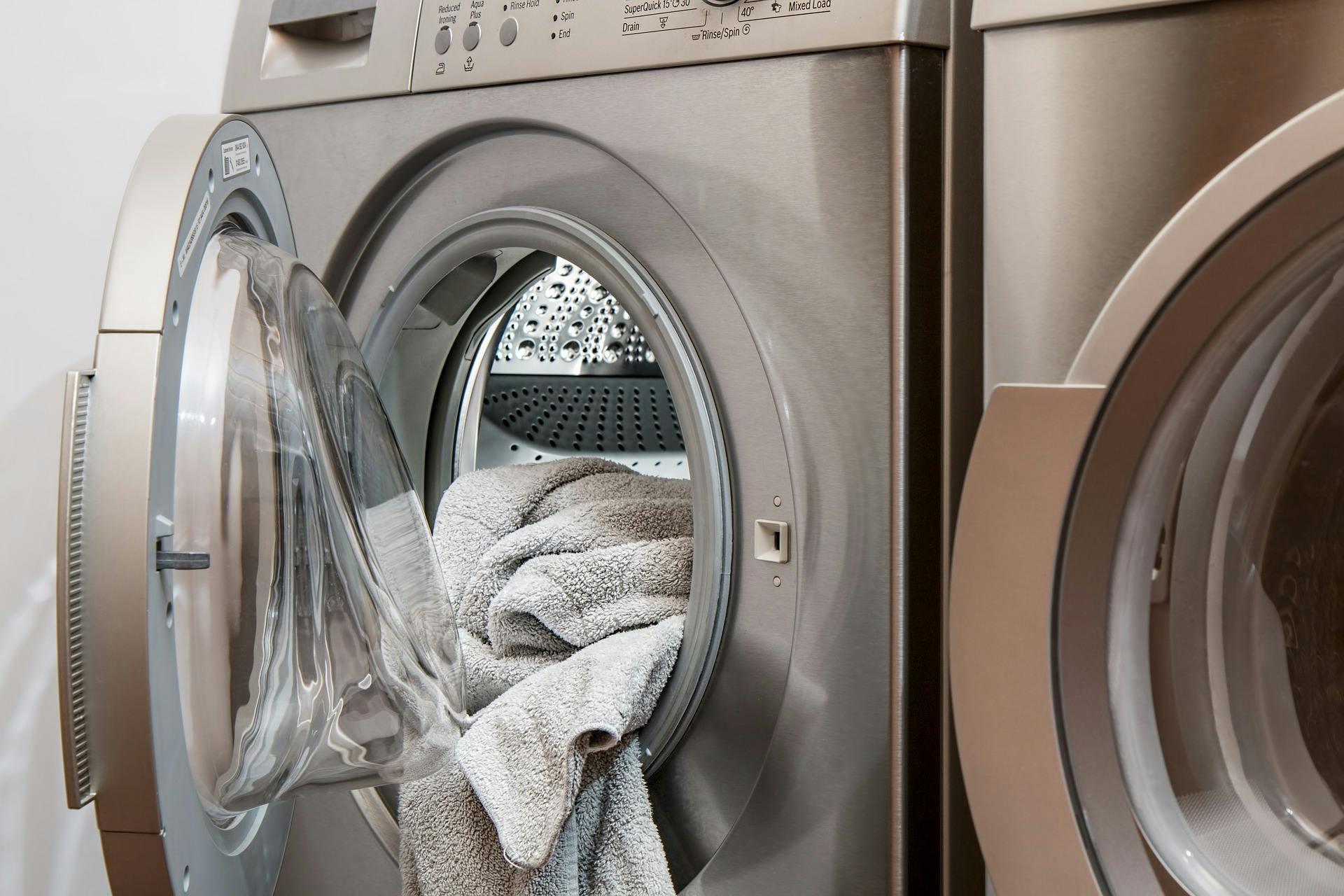 Close up of a dryer with a grey towel hanging out of the opening