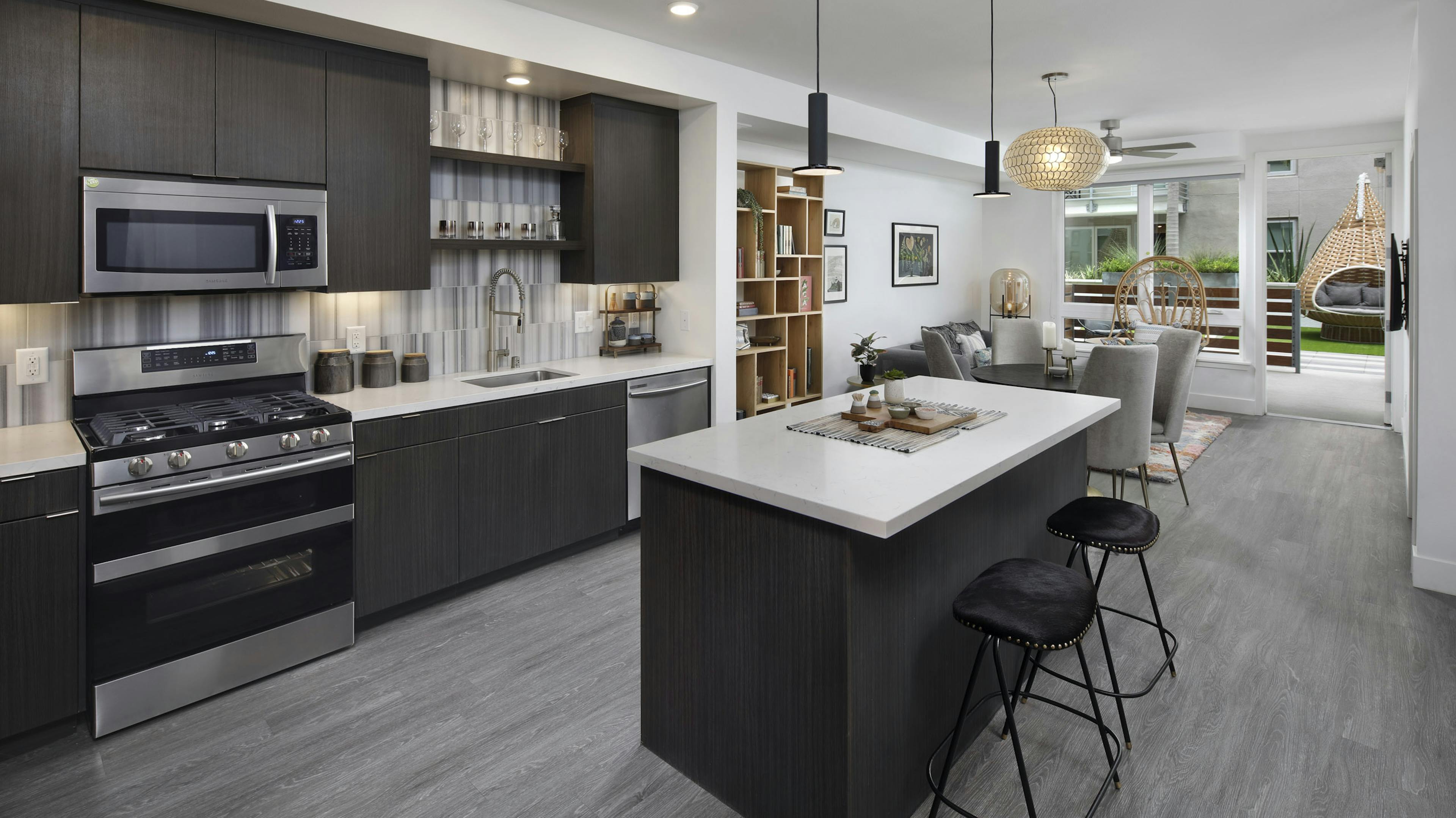 AMLI Park Broadway apartment kitchen with dark wood cabinets and light quartz countertops and furnished living room 