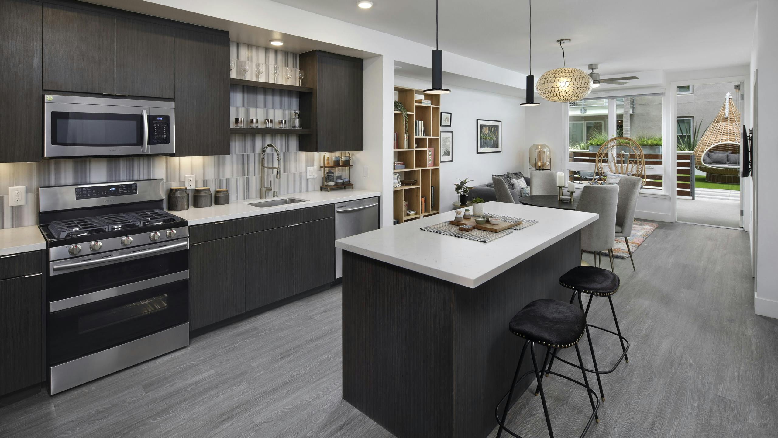 AMLI Park Broadway apartment kitchen with dark wood cabinets and light quartz countertops and furnished living room