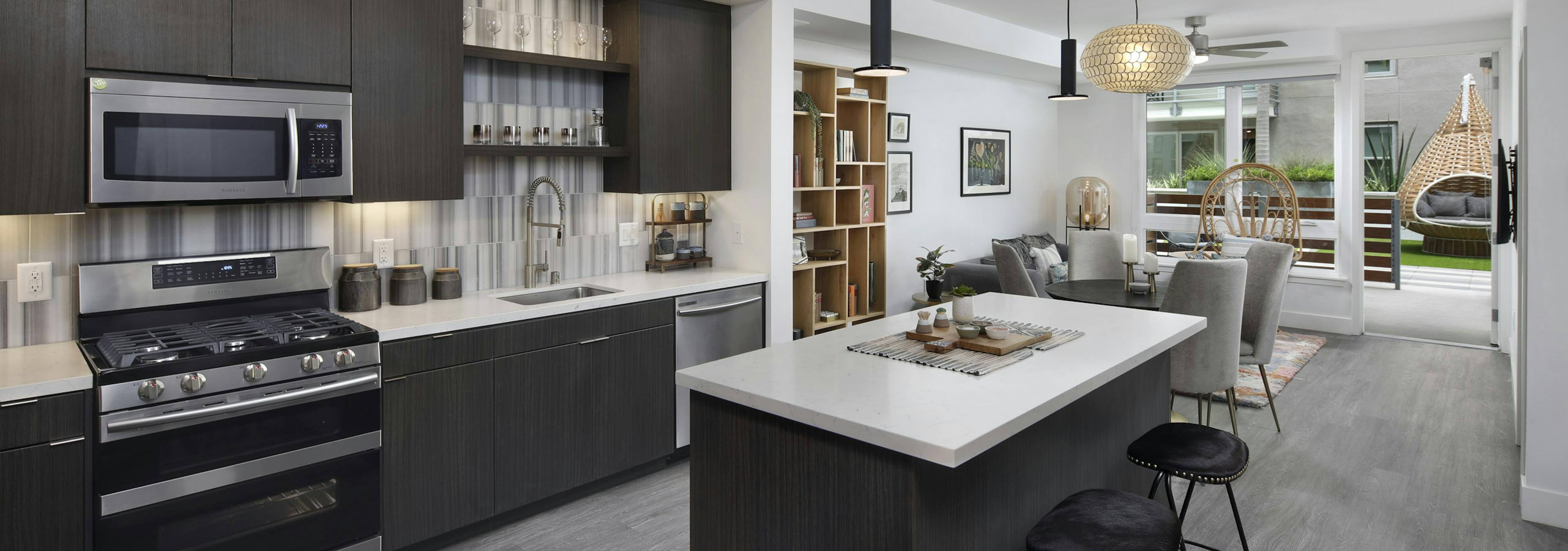 AMLI Park Broadway apartment kitchen with dark wood cabinets and light quartz countertops and furnished living room 