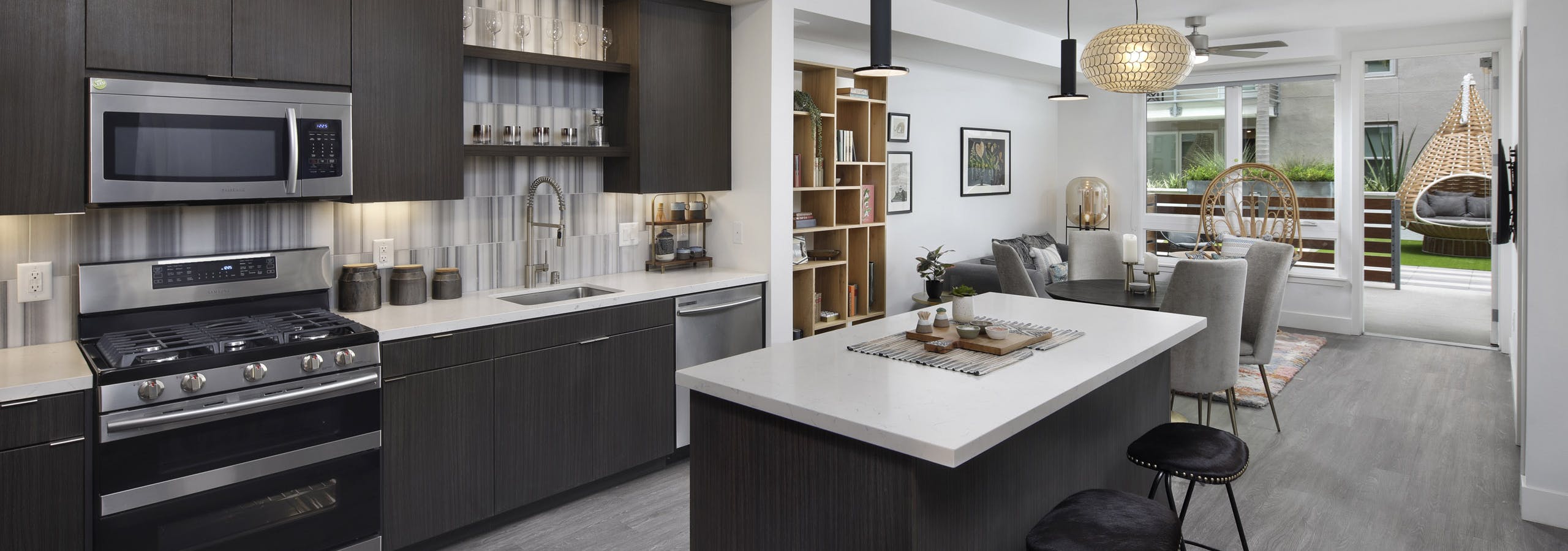 AMLI Park Broadway apartment kitchen with dark wood cabinets and light quartz countertops and furnished living room