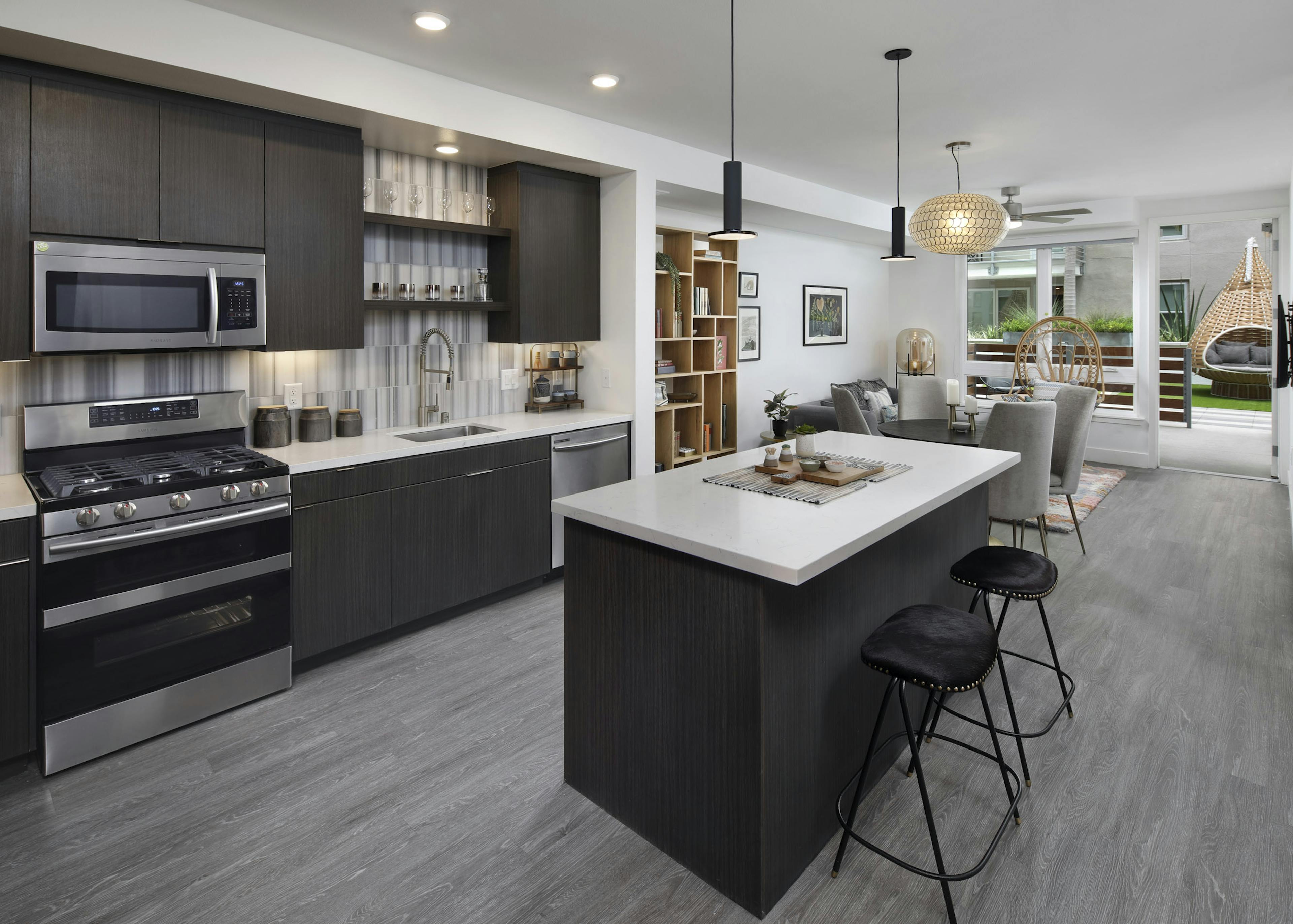 AMLI Park Broadway apartment kitchen with dark wood cabinets and light quartz countertops and furnished living room 