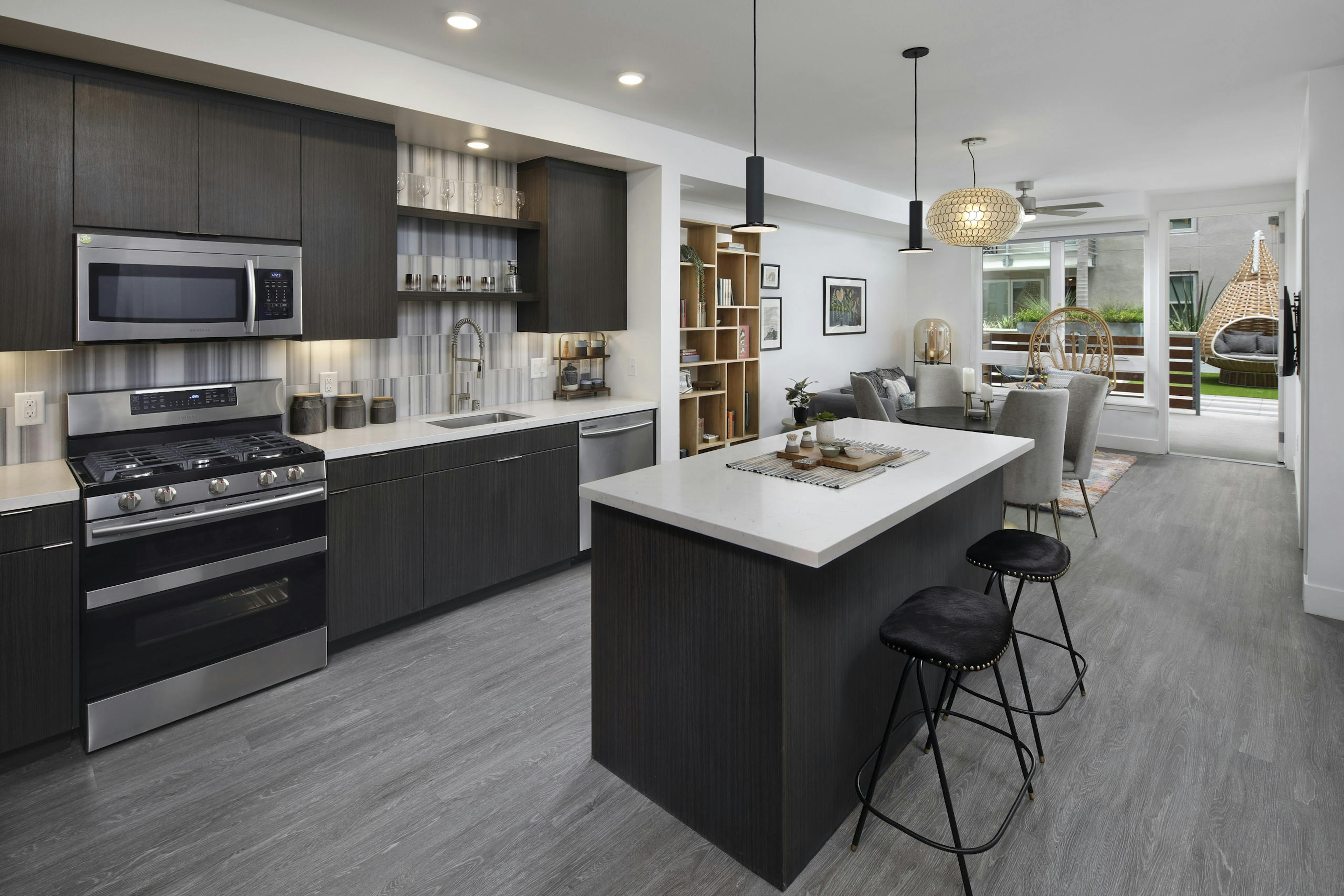 AMLI Park Broadway apartment kitchen with dark wood cabinets and light quartz countertops and furnished living room 