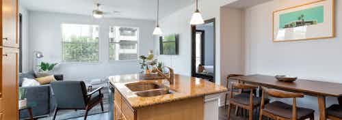 Daytime AMLI 300 apartment living room and kitchen with a kitchen island, under mount deep sink, and granite counter-tops