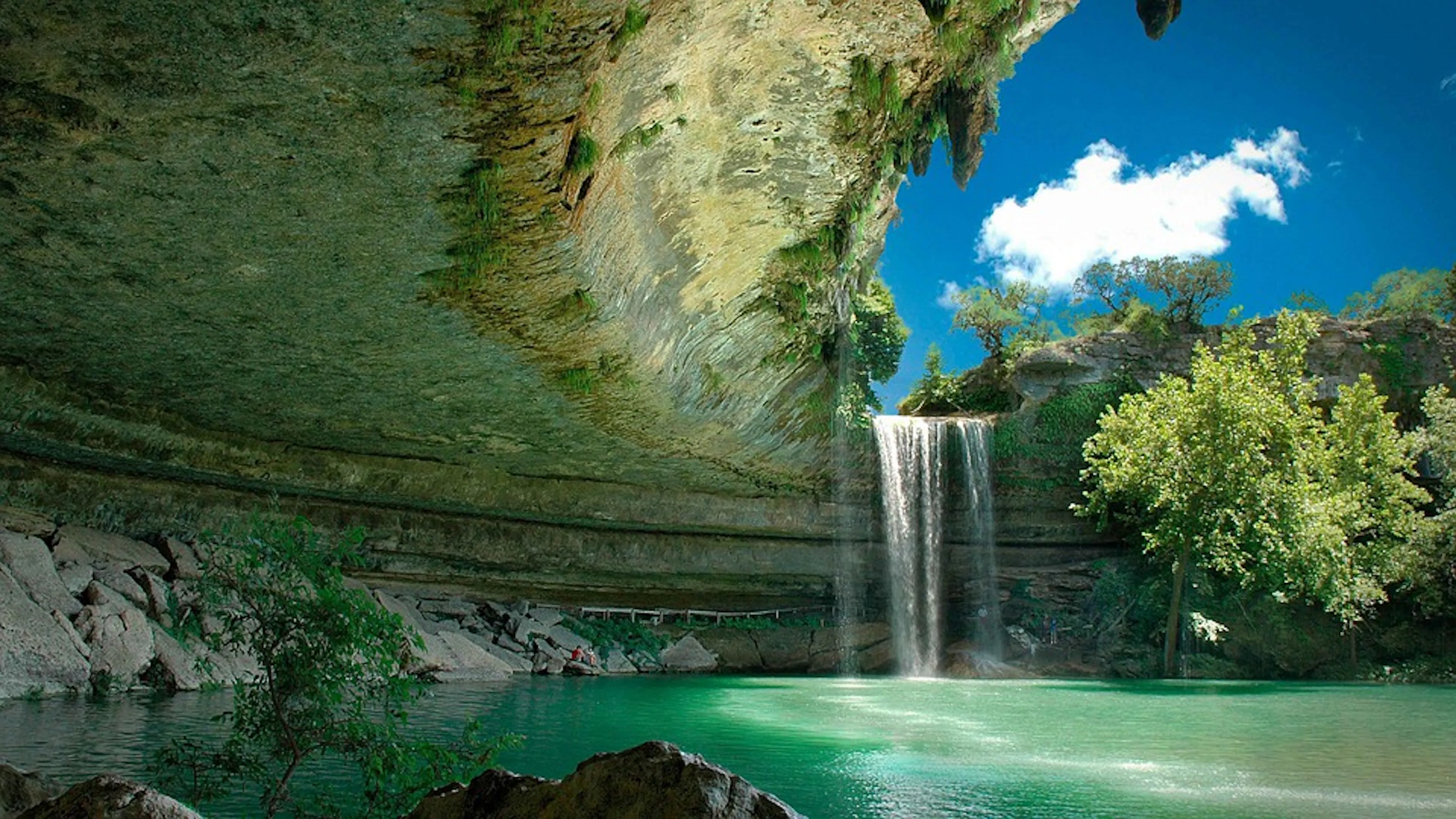 The Hamilton Pool Preserve in Texas with a waterfall falling into a grotto of blue water