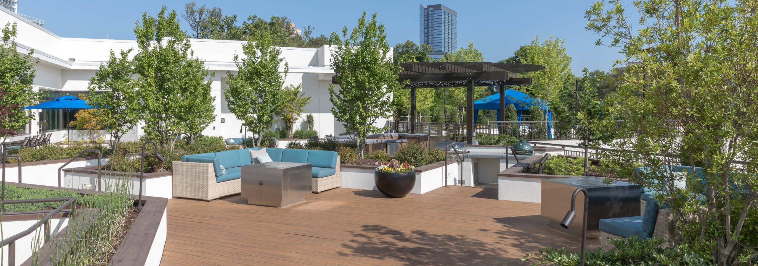 AMLI 3464 rooftop sundeck with scattered trees and blue outdoor couch with wooden pergola and blue canopy in the background