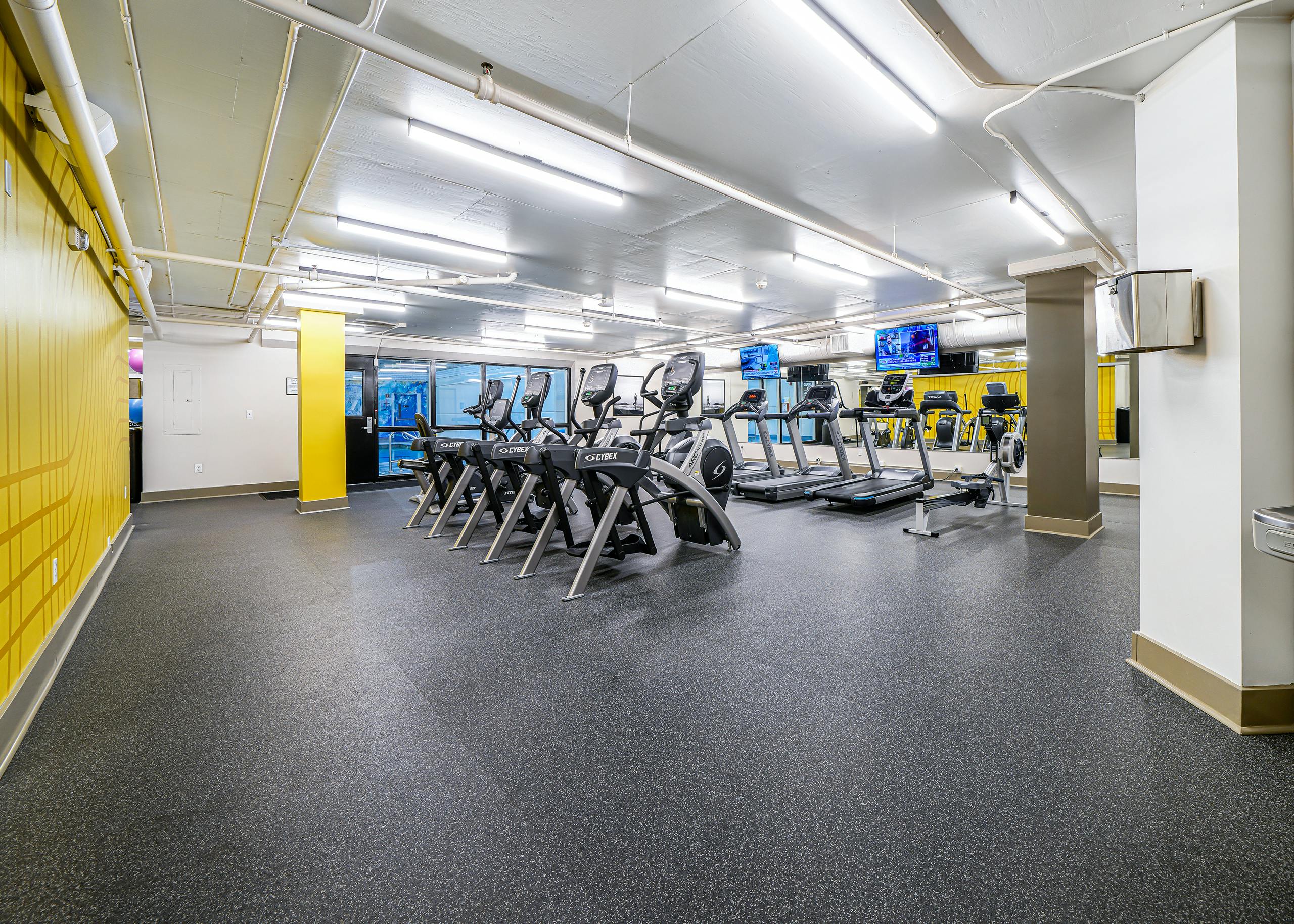 AMLI Bellevue Park fitness center with 2 rows of ellipticals and treadmills and a black padded floor and white ceiling