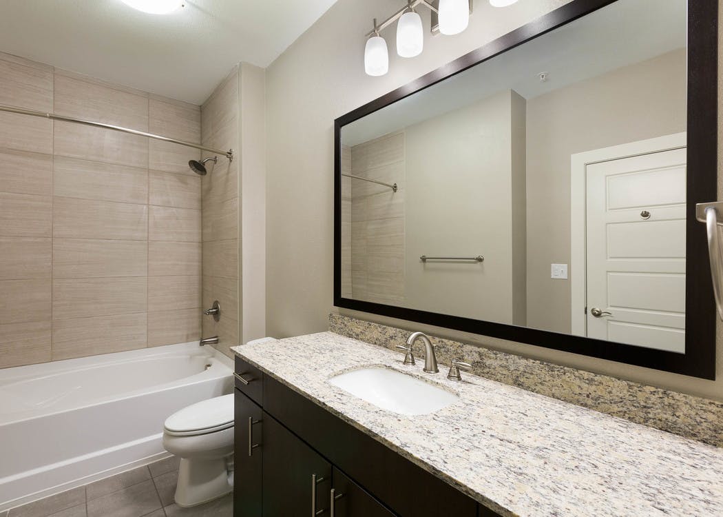 AMLI Covered Bridge bathroom with elegant granite countertop and white oversized bath tub with  tile surround