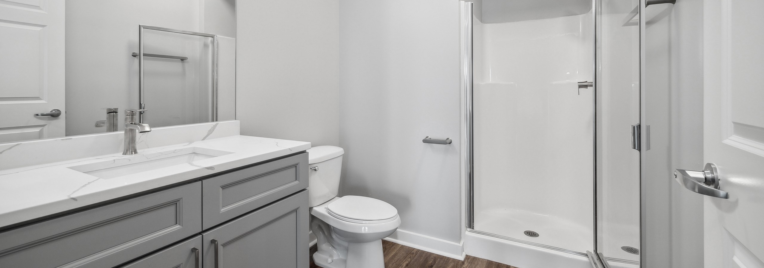 AMLI 900 bathroom featuring a gray vanity with white quartz counter and mirror above and a white toilet and stand up shower