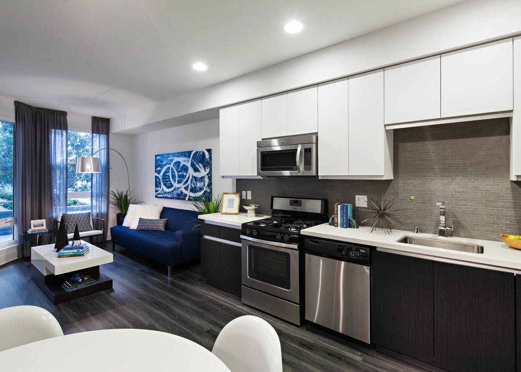 Interior of AMLI Lex on Orange apartment kitchen with white cabinetry and living room with blue couch and hard wood floors