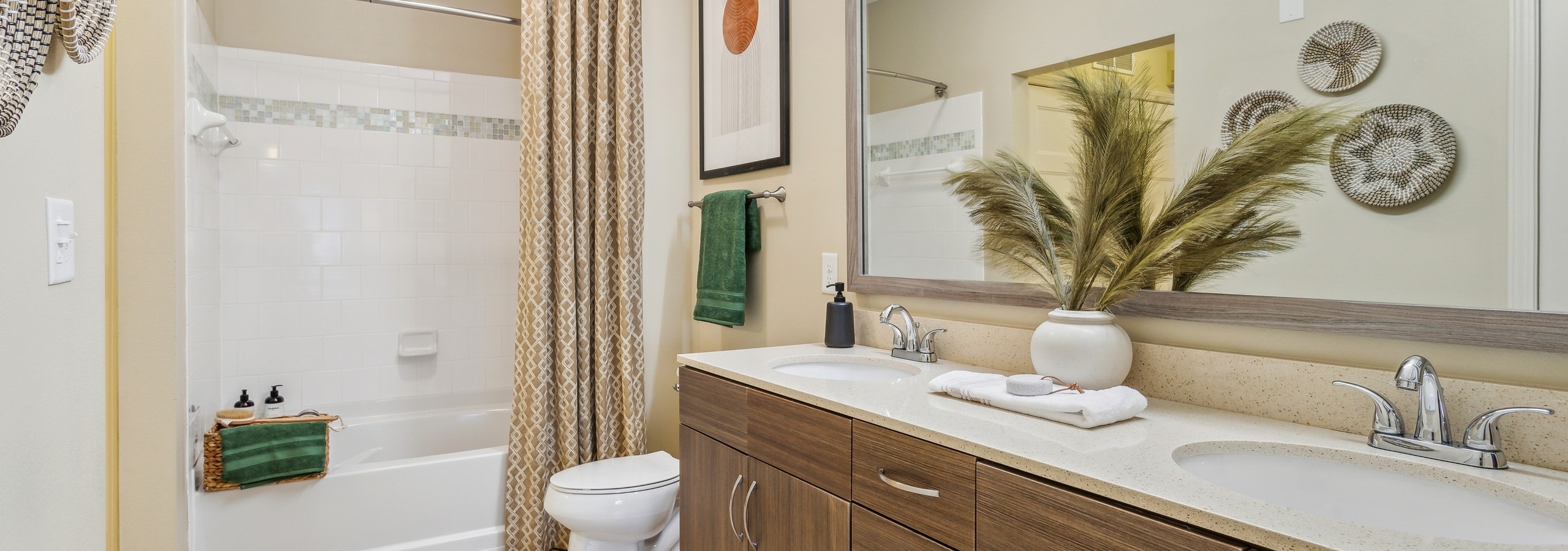 Interior view of AMLI Ponce Park bathroom with a double vanity mirror and white toilet and shower tub with beige curtain