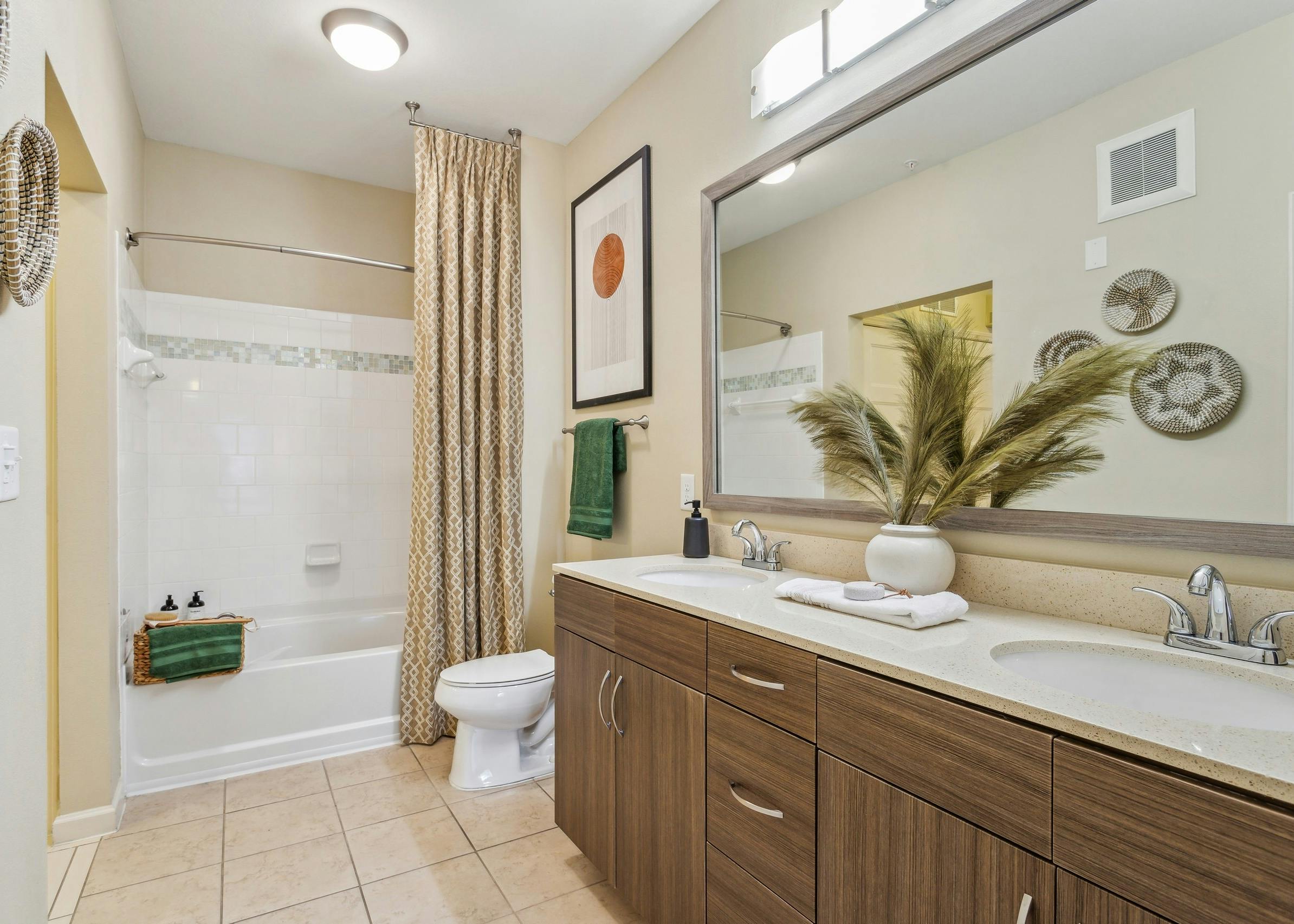 Interior view of AMLI Ponce Park bathroom with a double vanity mirror and white toilet and shower tub with beige curtain