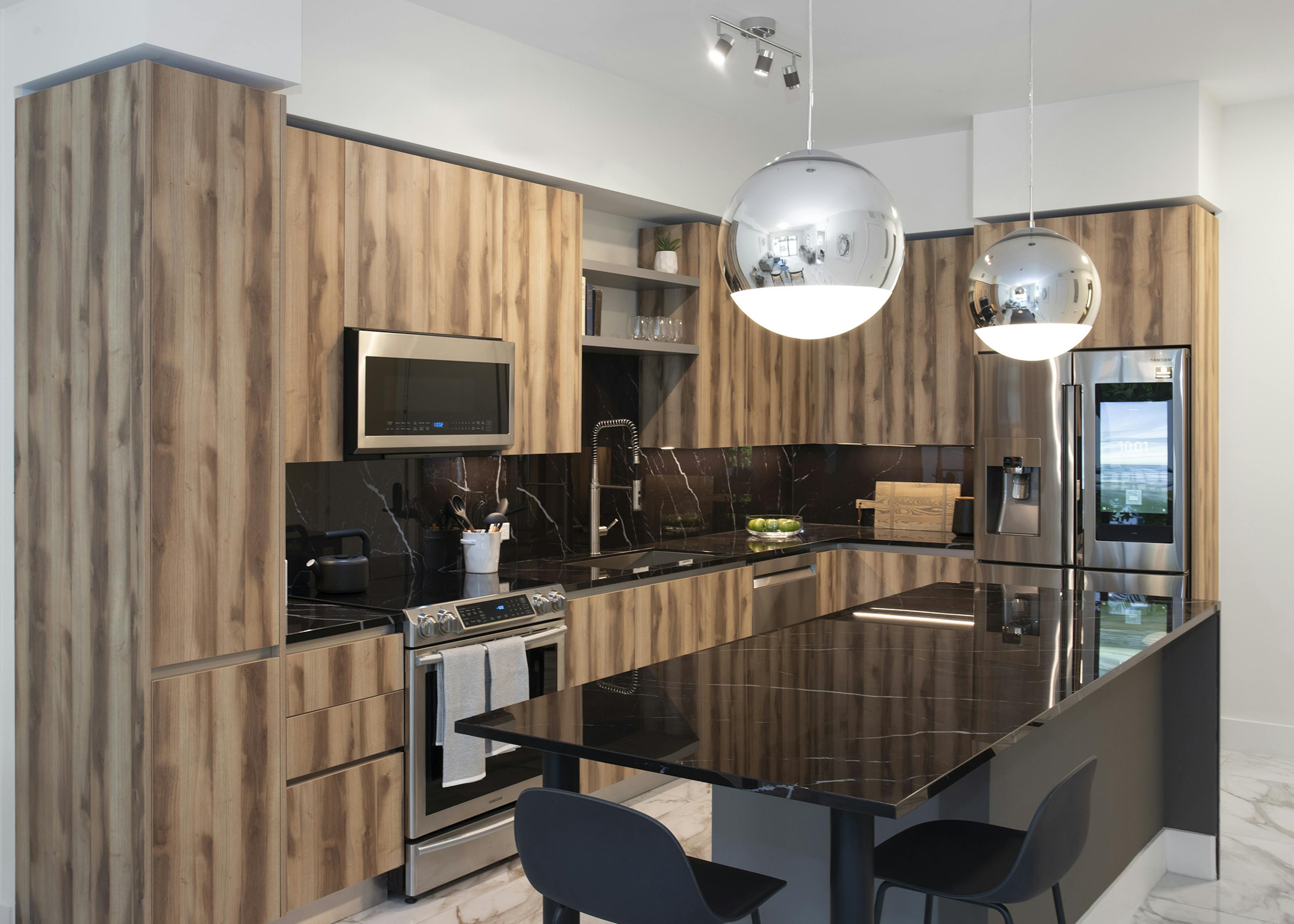 AMLI Midtown Miami apartment kitchen with black marble island and two stools and zebra wood cabinets and marble backsplash 