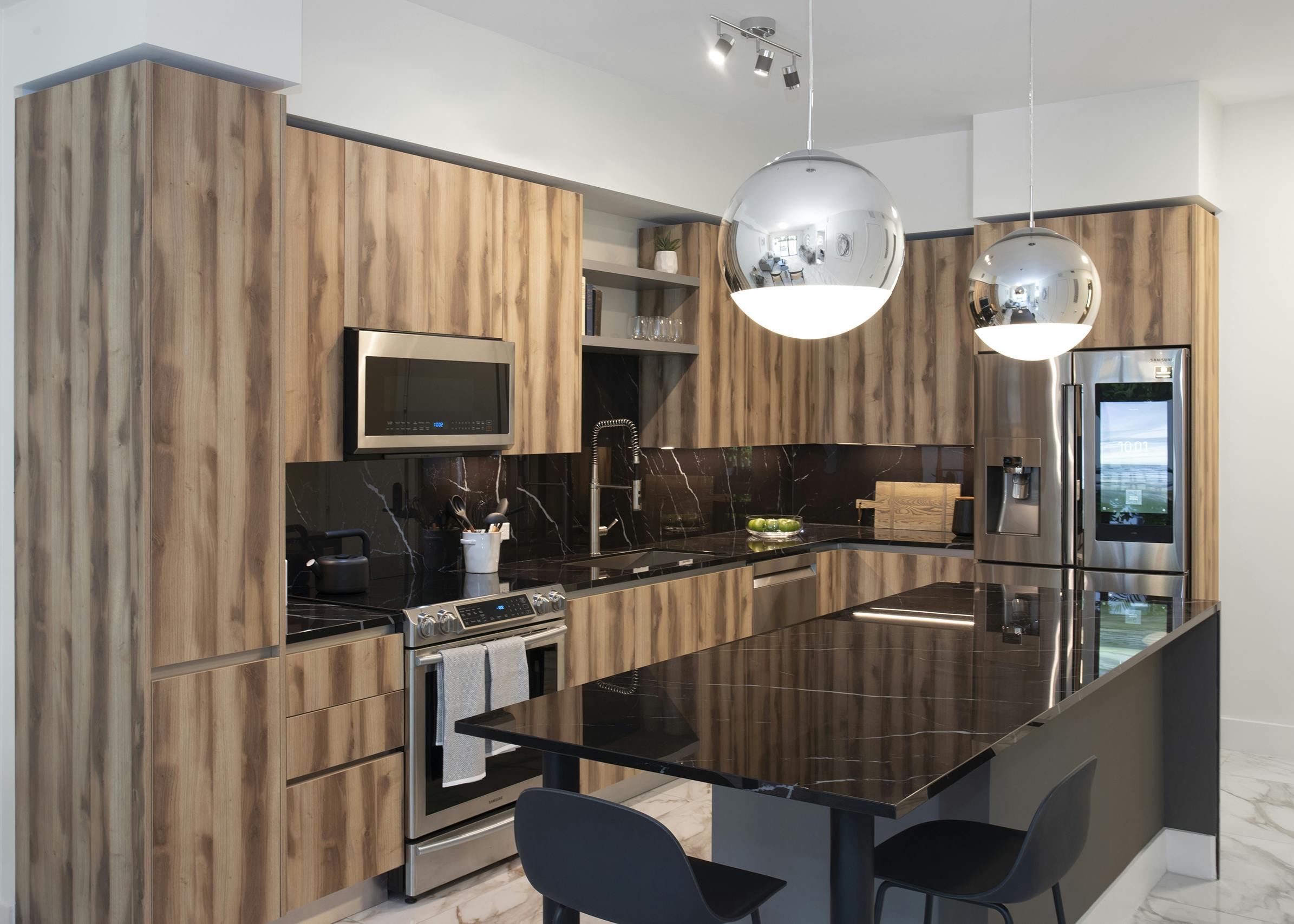 AMLI Midtown Miami apartment kitchen with black marble island and two stools and zebra wood cabinets and marble backsplash