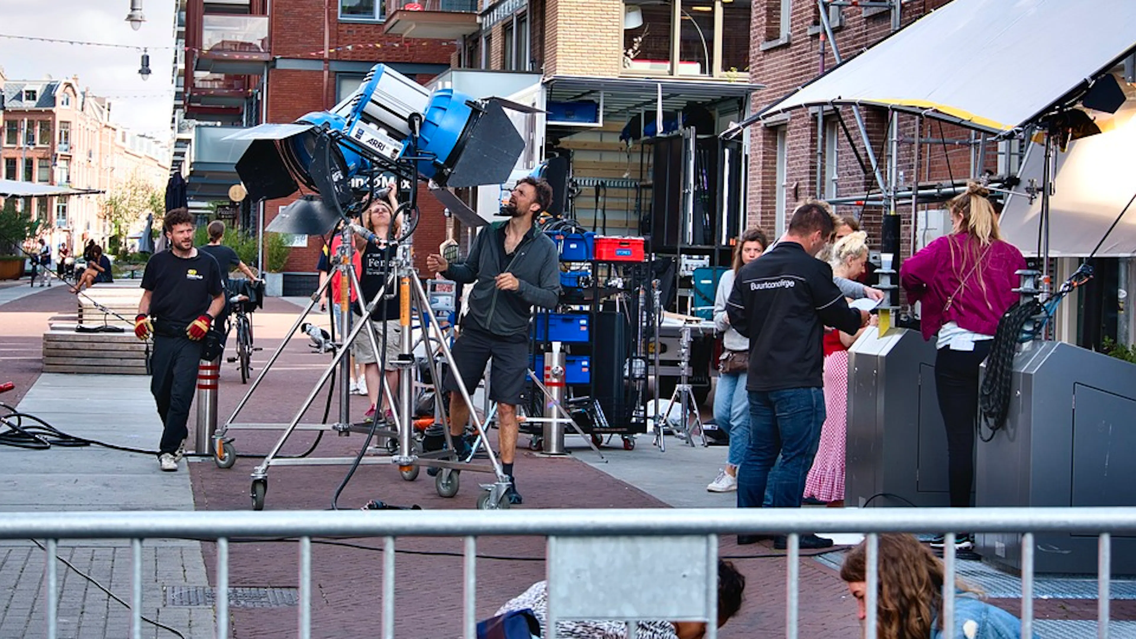 A film set and crew outside in a courtyard beside some modern apartment buildings
