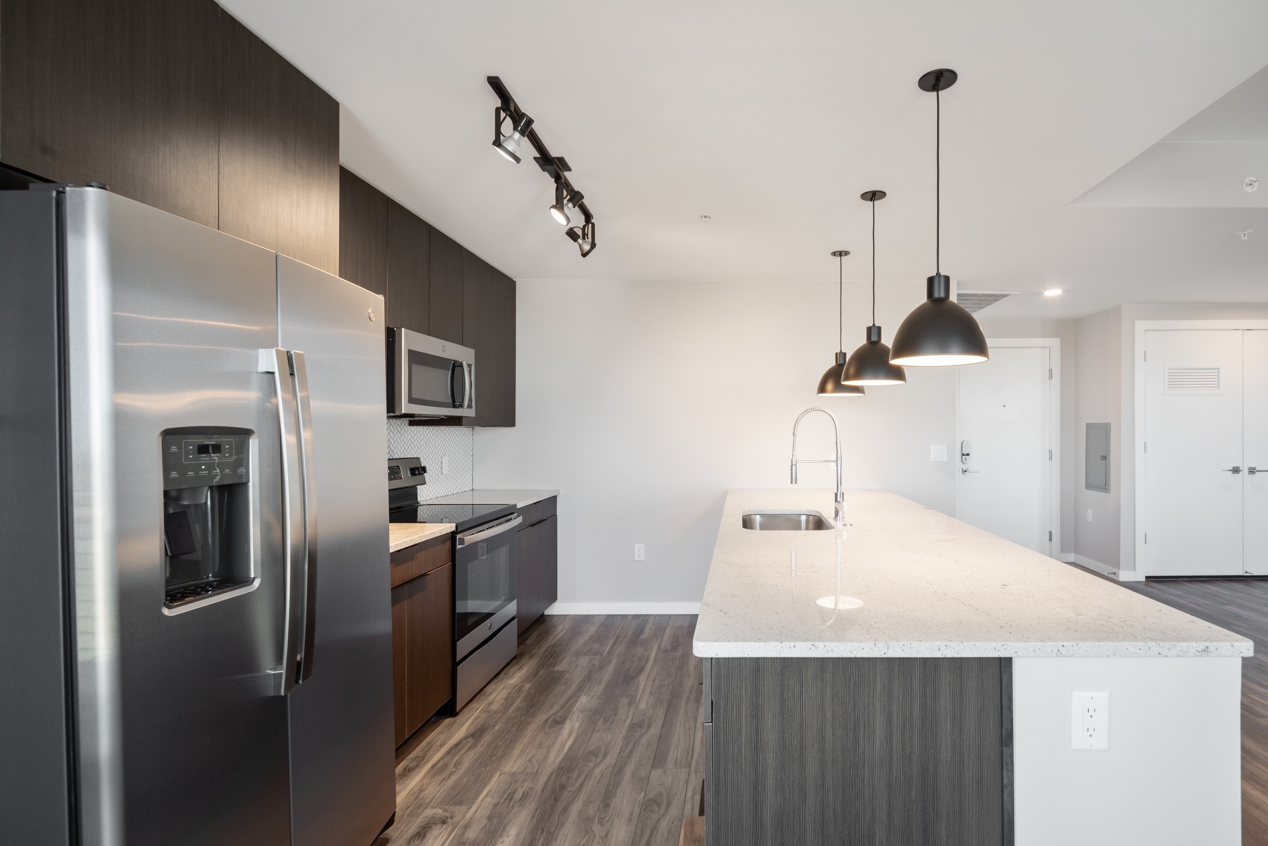 Close up view of luxurious AMLI at Uptown apartment kitchen with stainless steel appliances and white granite countertops