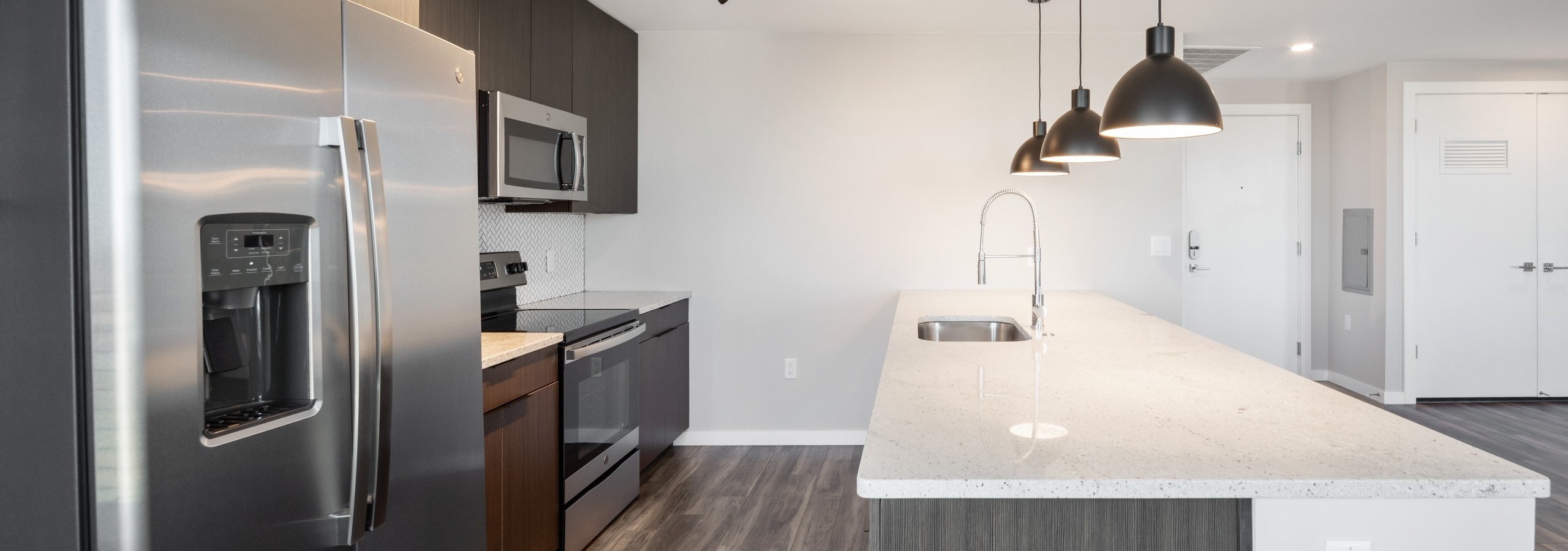 Close up view of luxurious AMLI at Uptown apartment kitchen with stainless steel appliances and white granite countertops