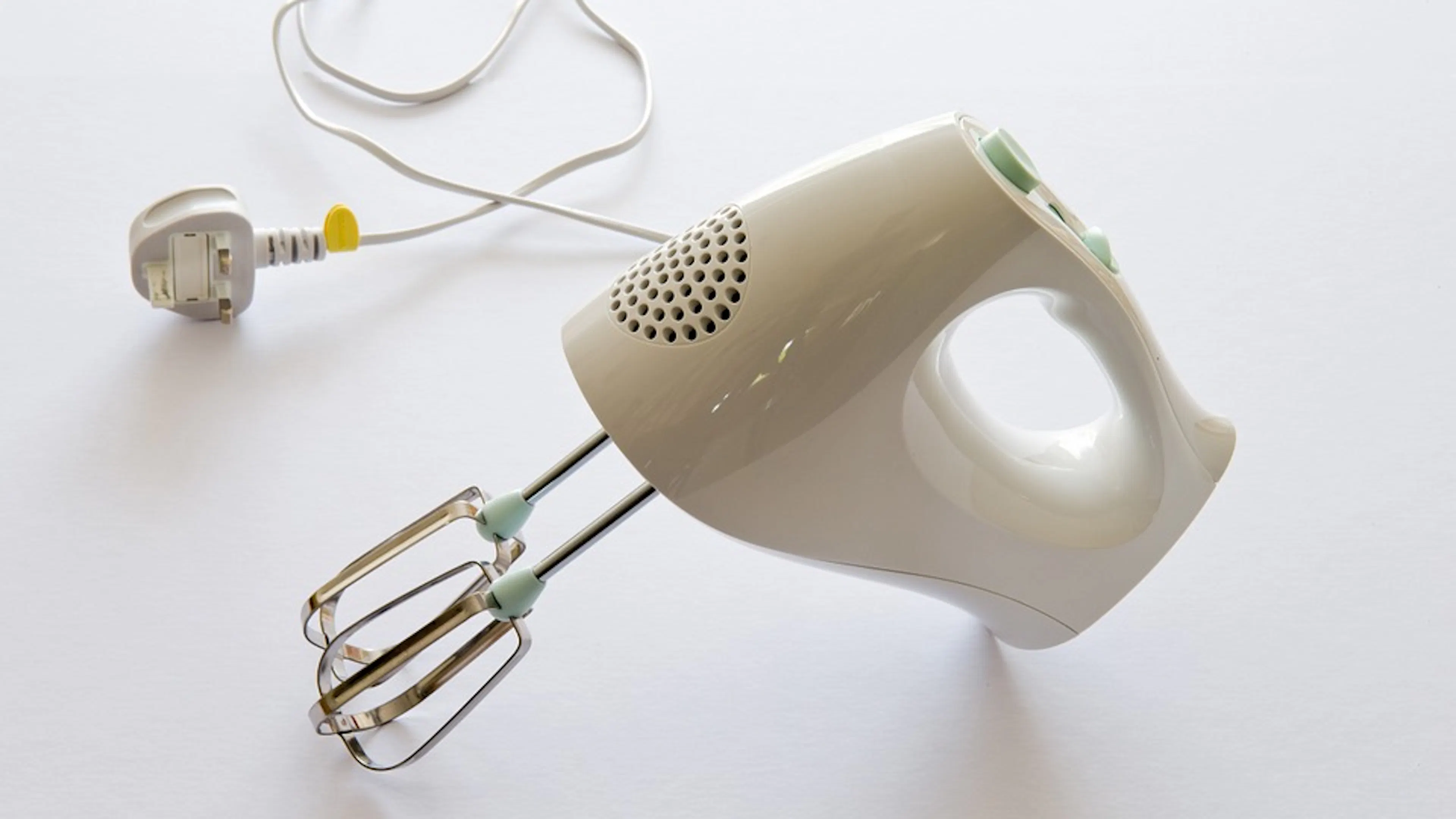 A white hand blender with the cord and plug lying next to it