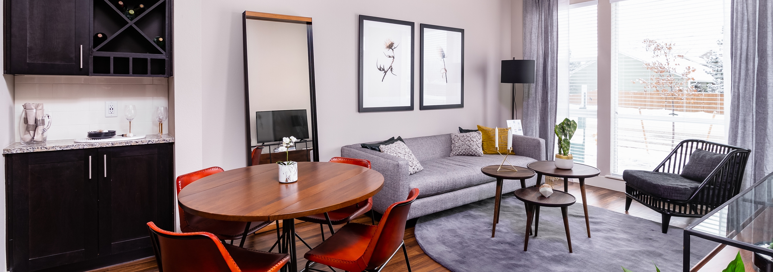 Interior of apartment at AMLI Littleton Village with dining table, chairs and living room with large window overlooking patio