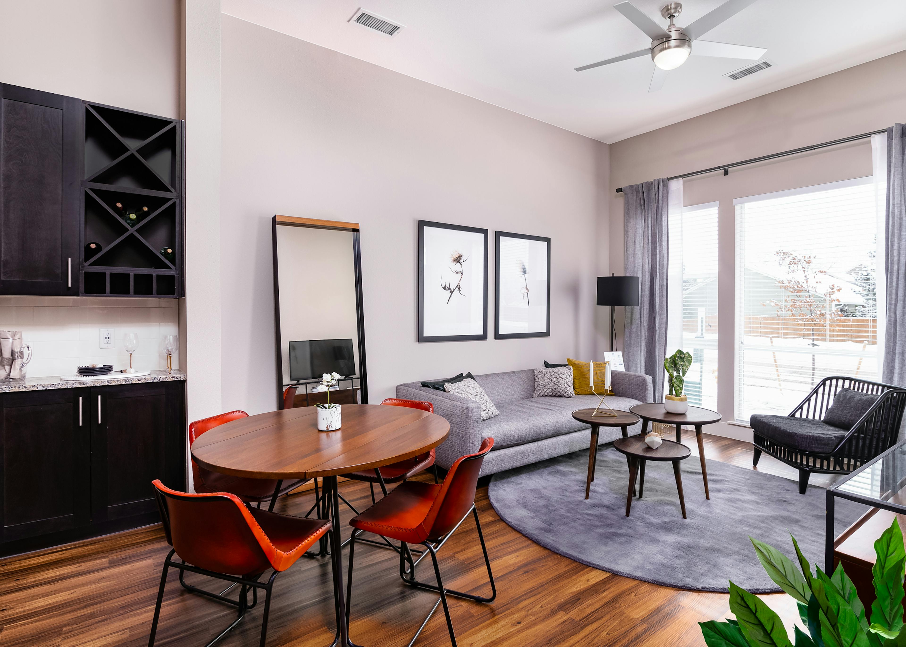 Interior of apartment at AMLI Littleton Village with dining table, chairs and living room with large window overlooking patio