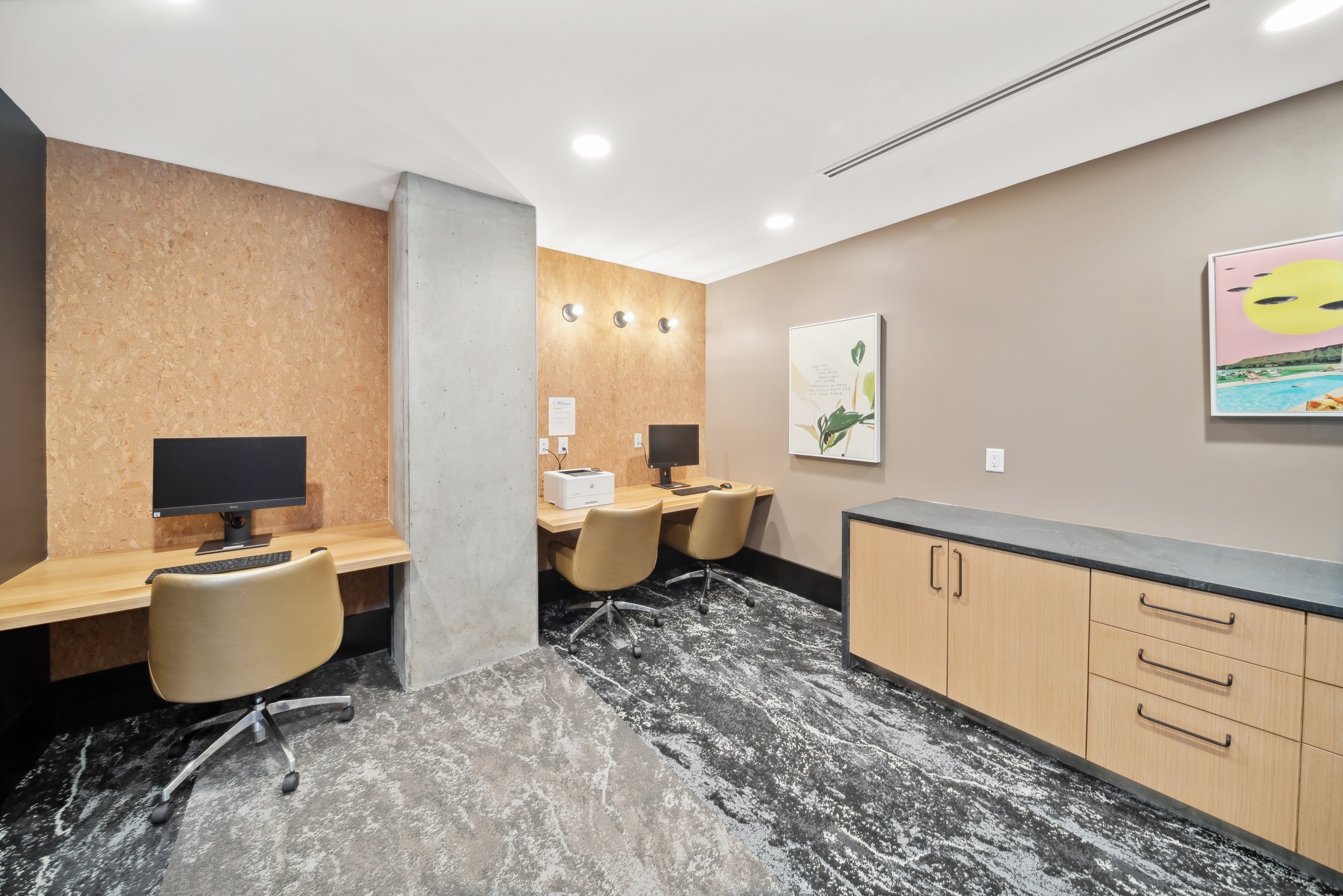 AMLI RiNo business center with wood counter top desks and tan leather chairs and wood credenza and grey veined flooring