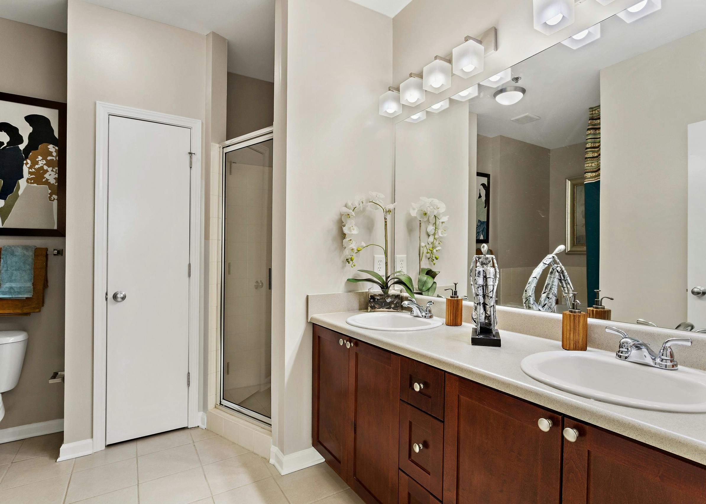 Bathroom with dark wood vanity with two sinks and large mirror above and walk in shower at AMLI Lindbergh apartments