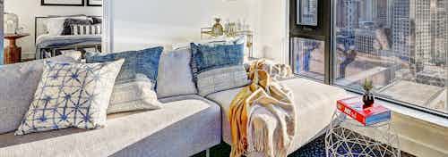 Interior view of apartment of AMLI Arc living room with ample seating and window and peek inside bedroom with open door