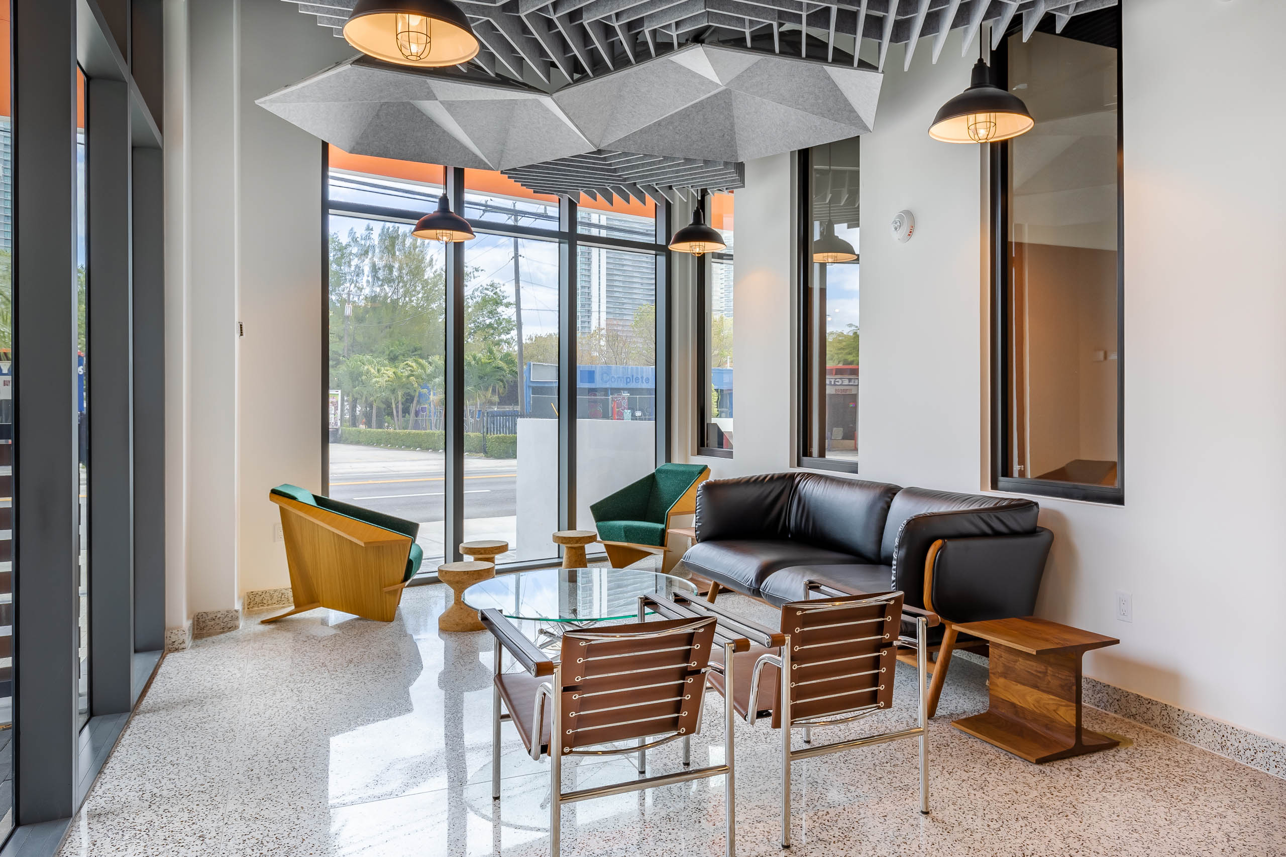 The hub lounge at AMLI Midtown Miami apartments with black sofa and glass coffee table with modern seating and window view