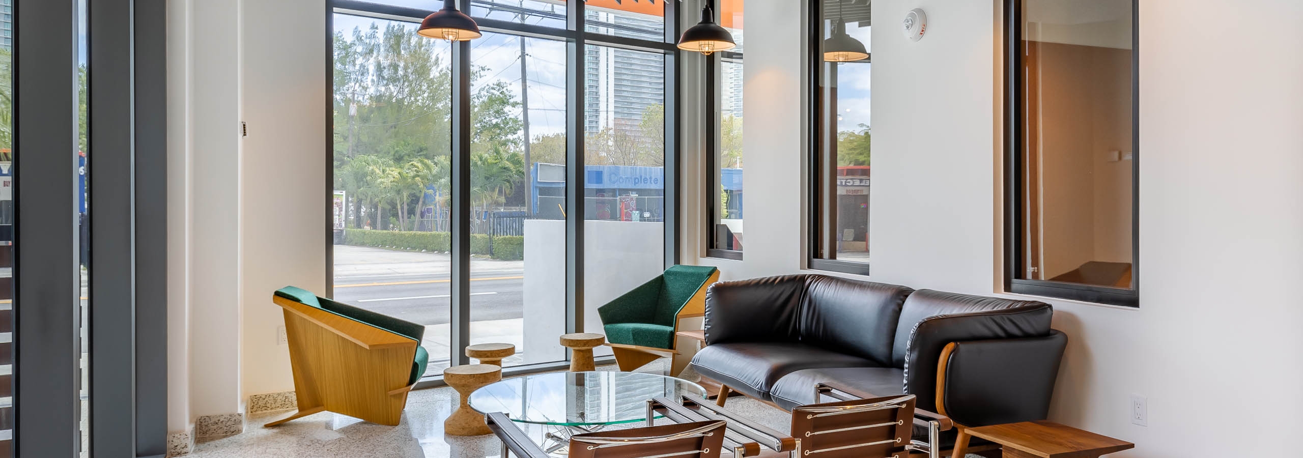 The hub lounge at AMLI Midtown Miami apartments with black sofa and glass coffee table with modern seating and window view