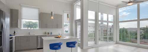 AMLI Buckhead kitchen with grey wood cabinets and an island with blue barstools and floor to ceiling windows with nature view