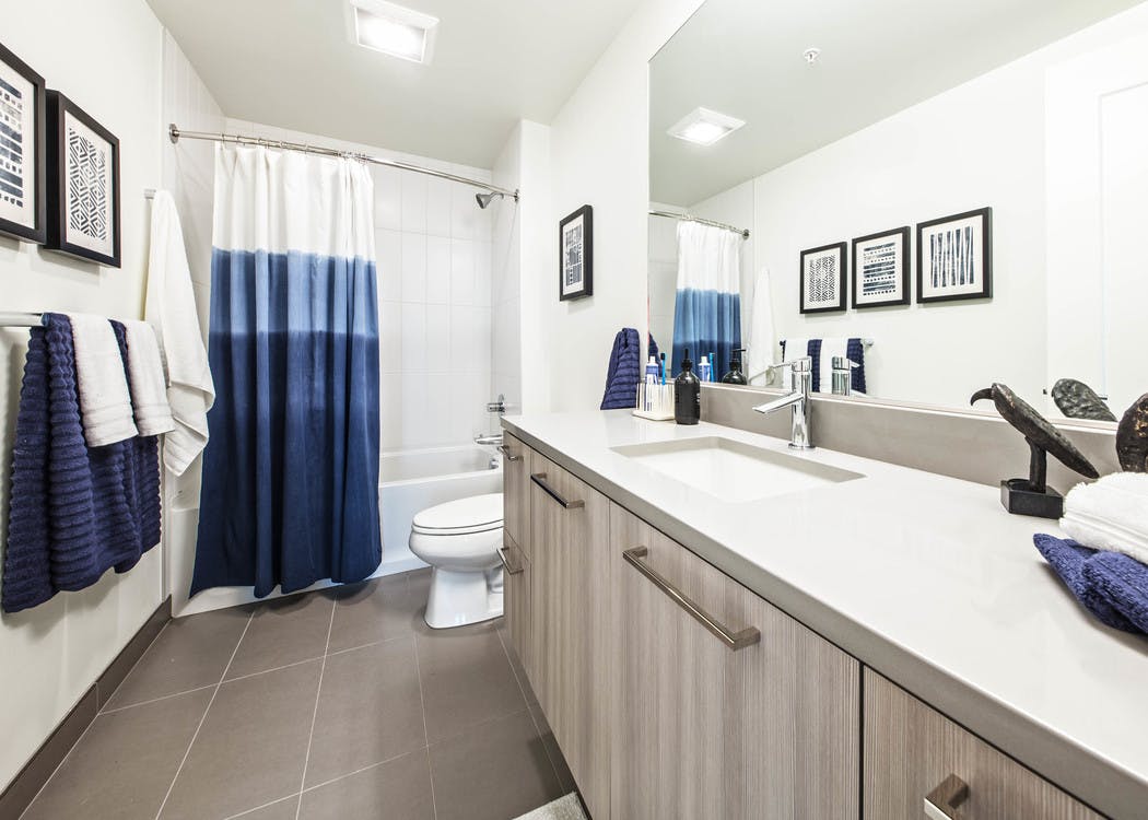 Interior view of AMLI Arc apartment bathroom with toilet shower and tub combination with white quartz counter tops